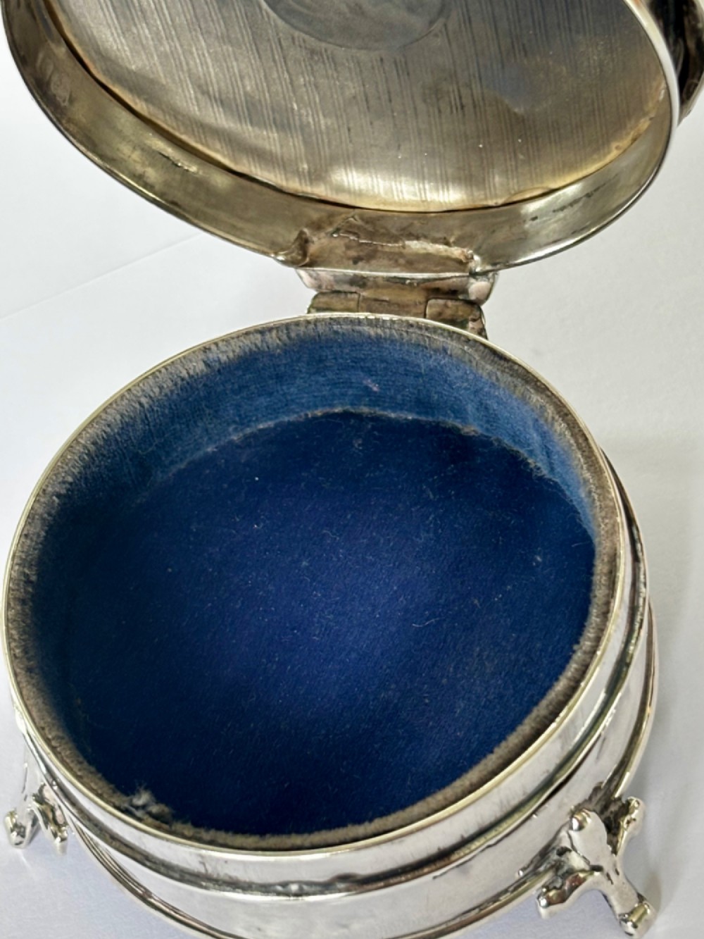 A circular George V sterling silver trinket box featuring engine-turned lid decoration, an engraved central cartouche, and four short pad feet. View XI
