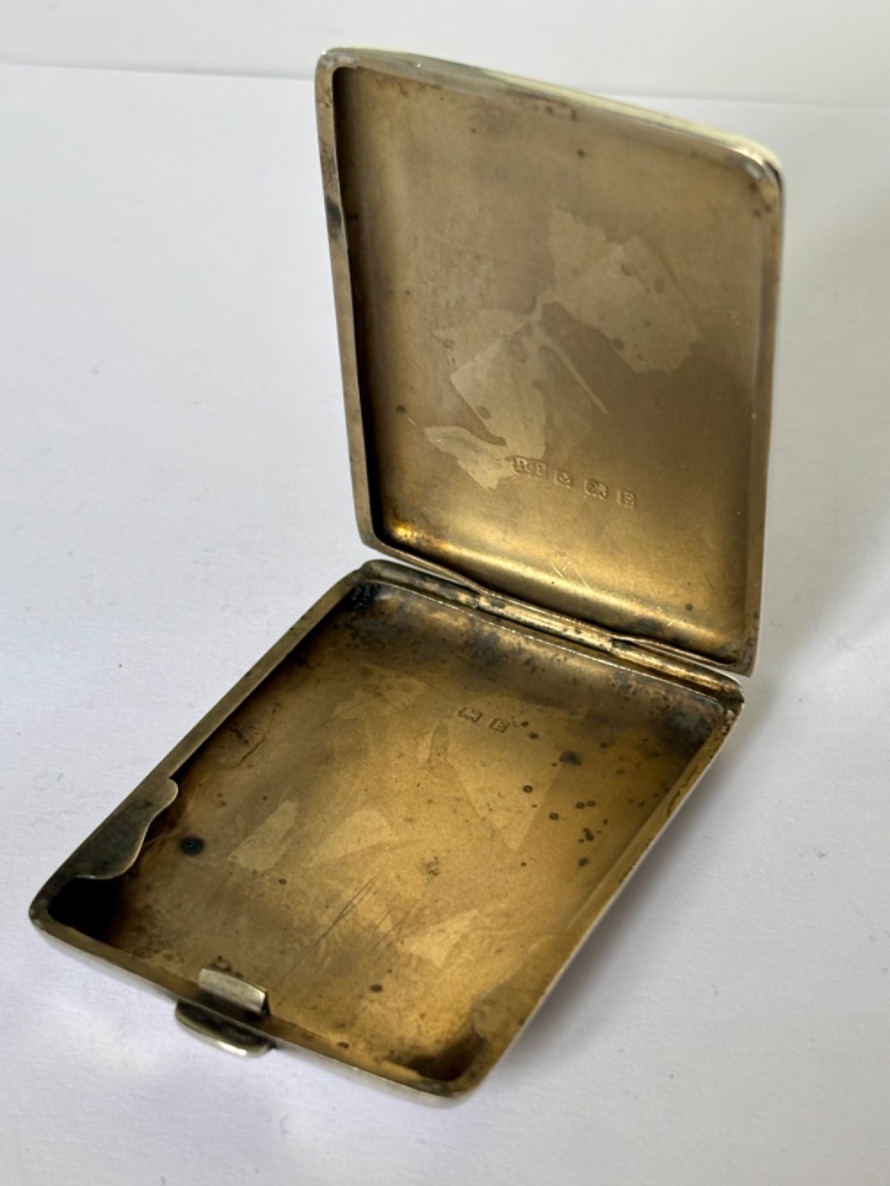 Rectangular sterling silver matchbook case featuring engine-turned geometric linear pattern and a central monogrammed cartouche. View V
