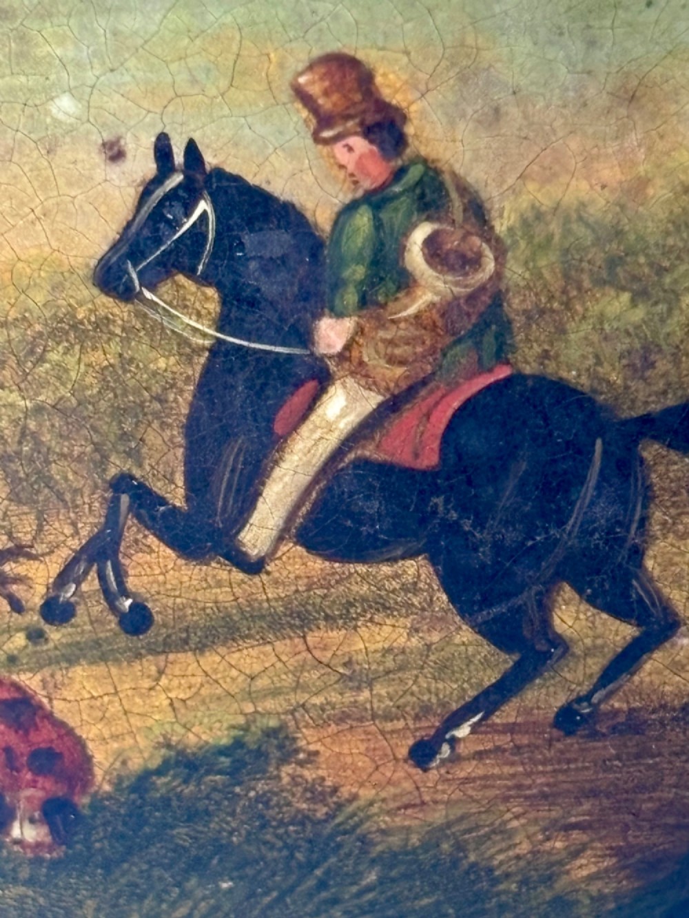 A circular black papier-mache snuff box featuring a hand-painted scene on the lid depicting a horseman and hunting dogs. View IV