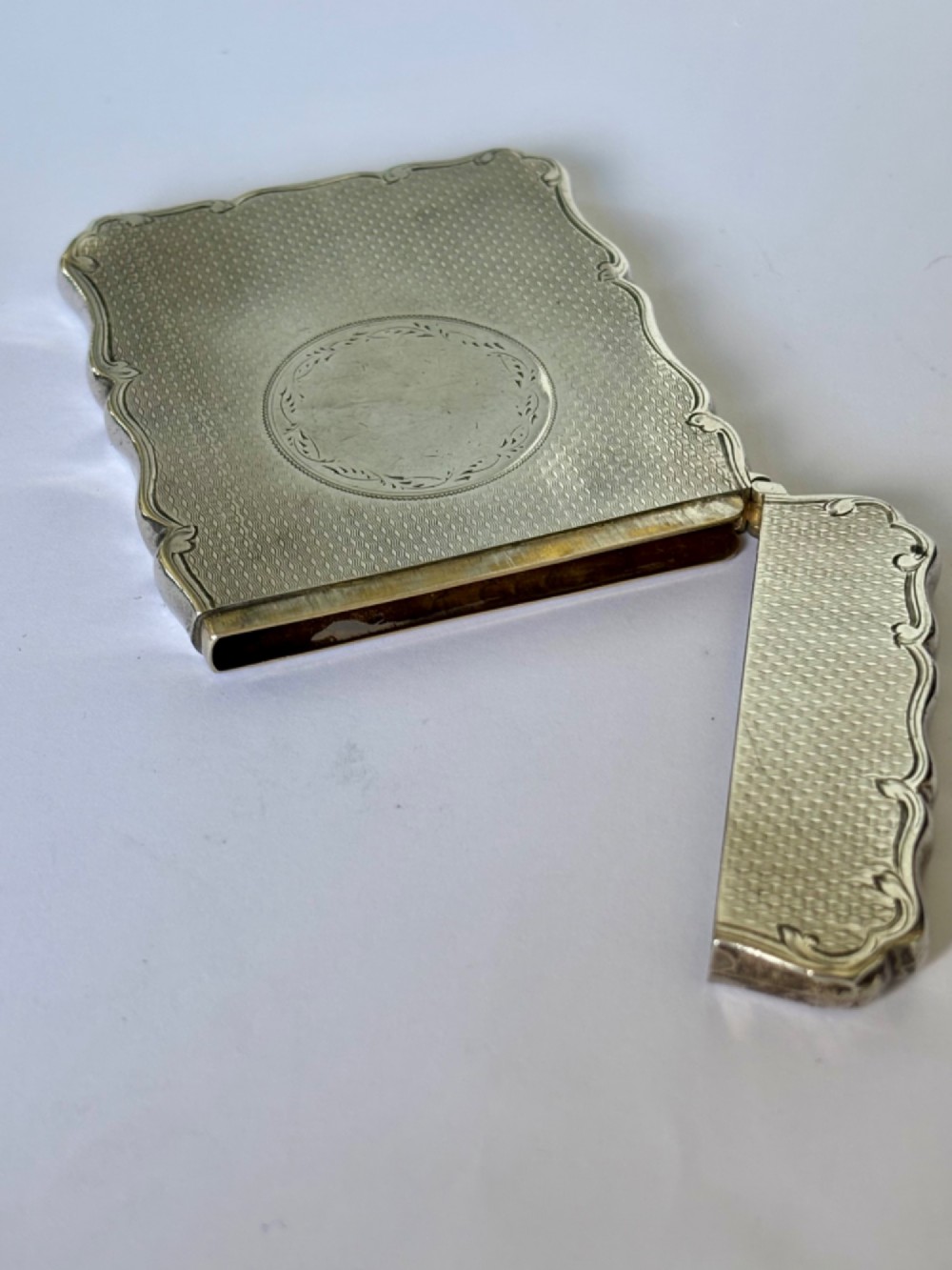 An antique Victorian sterling silver calling card case featuring shaped wavy edges, an engine-turned pattern, and an oval central cartouche. View III