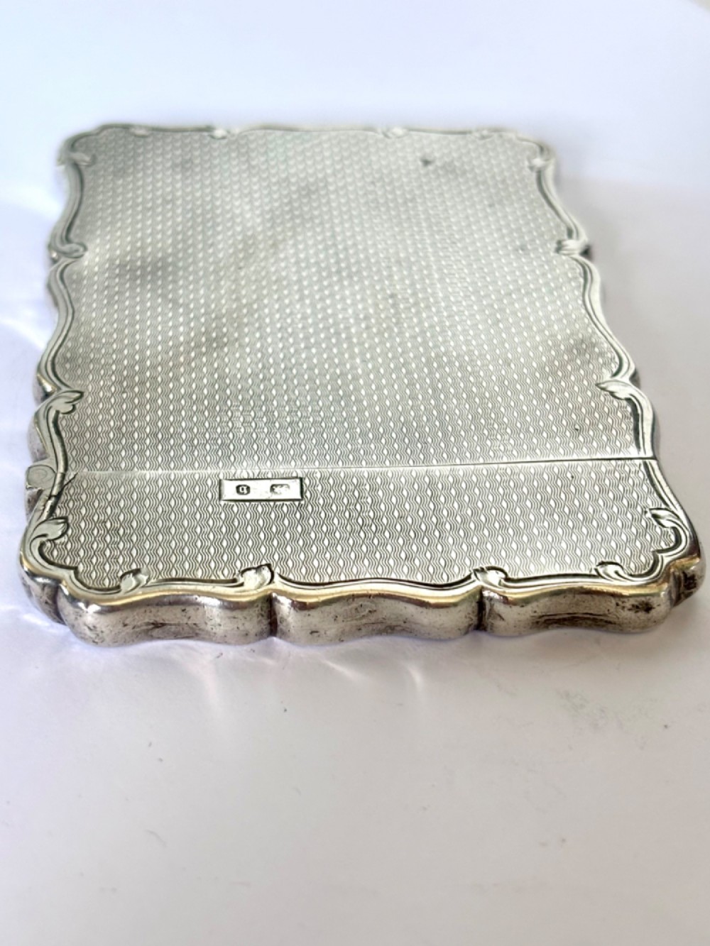 An antique Victorian sterling silver calling card case featuring shaped wavy edges, an engine-turned pattern, and an oval central cartouche. View VII