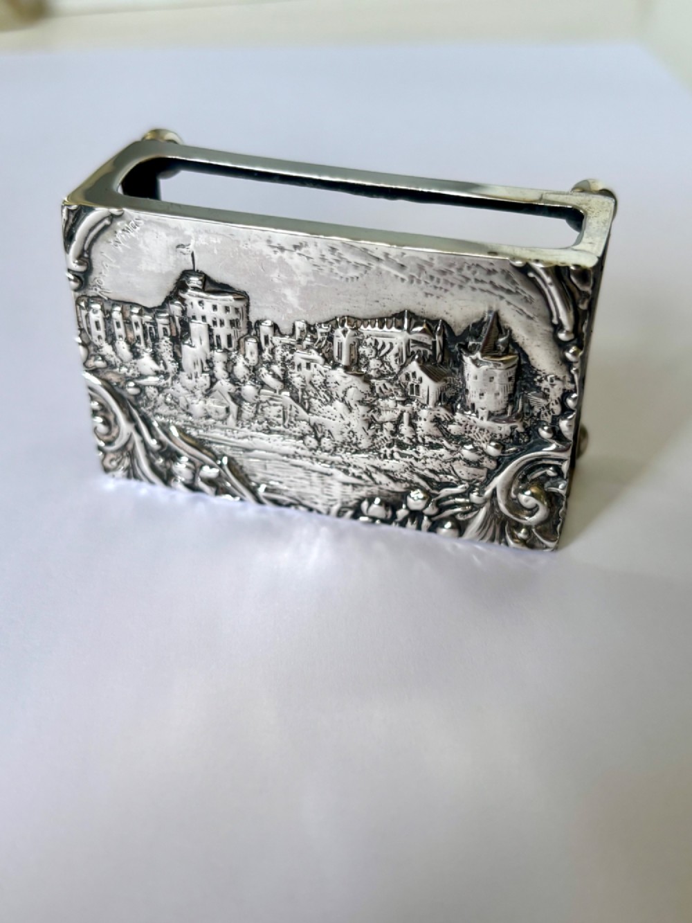 A rectangular silver matchbox cover featuring an embossed relief depicting Windsor Castle surrounded by scrollwork borders. View II