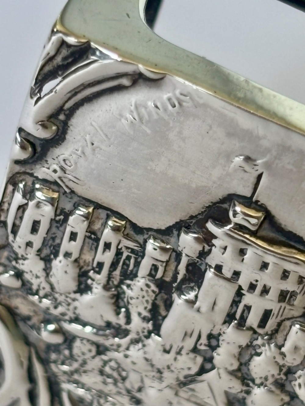 A rectangular silver matchbox cover featuring an embossed relief depicting Windsor Castle surrounded by scrollwork borders. View III
