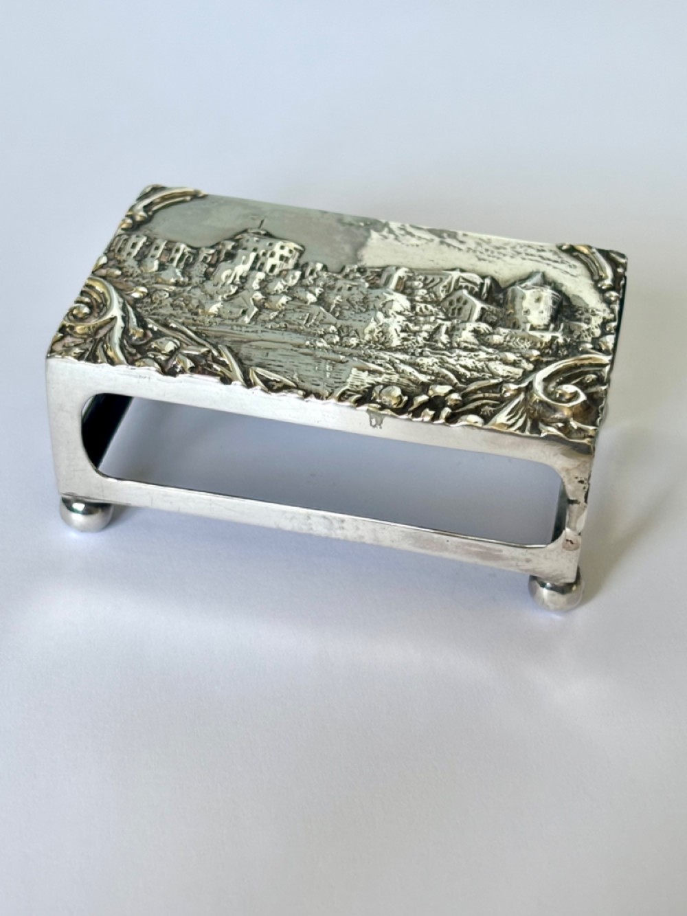 A rectangular silver matchbox cover featuring an embossed relief depicting Windsor Castle surrounded by scrollwork borders. View IV