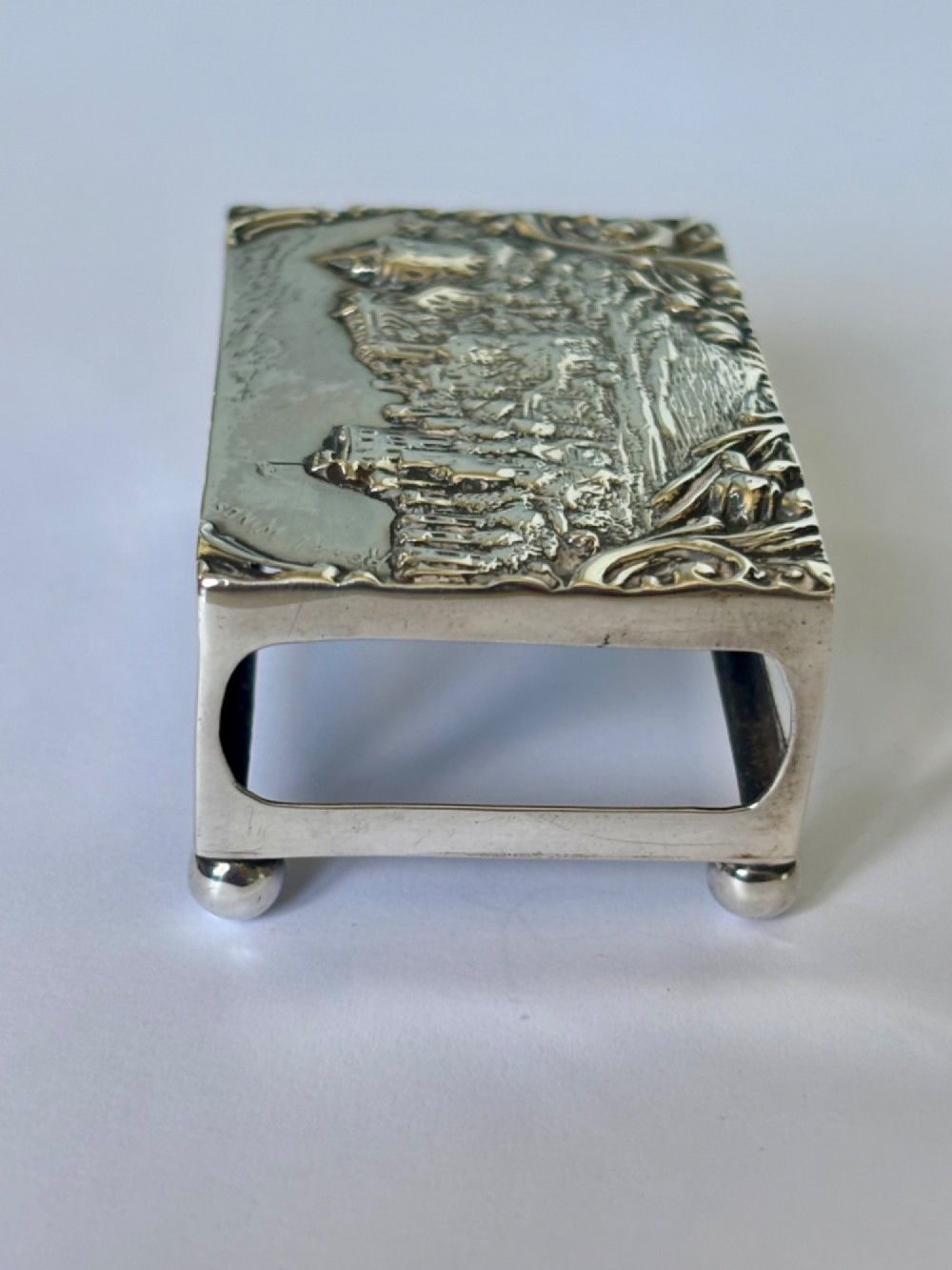 A rectangular silver matchbox cover featuring an embossed relief depicting Windsor Castle surrounded by scrollwork borders. View VII