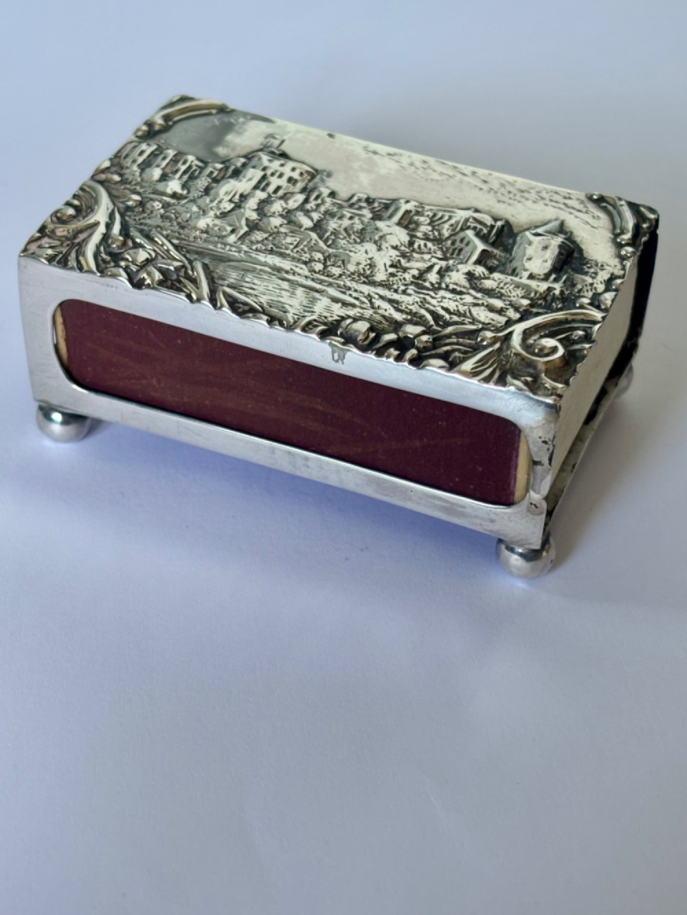 A rectangular silver matchbox cover featuring an embossed relief depicting Windsor Castle surrounded by scrollwork borders. View XI