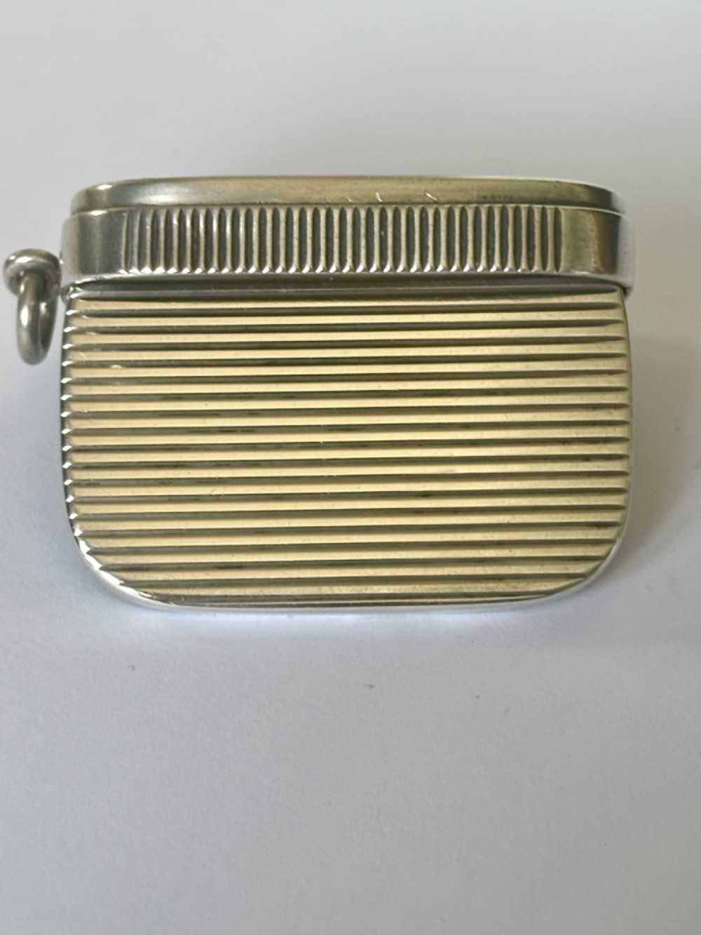 A small rectangular Victorian silver vesta case featuring horizontal reeded engine-turned decoration and an attached side suspension ring. View V