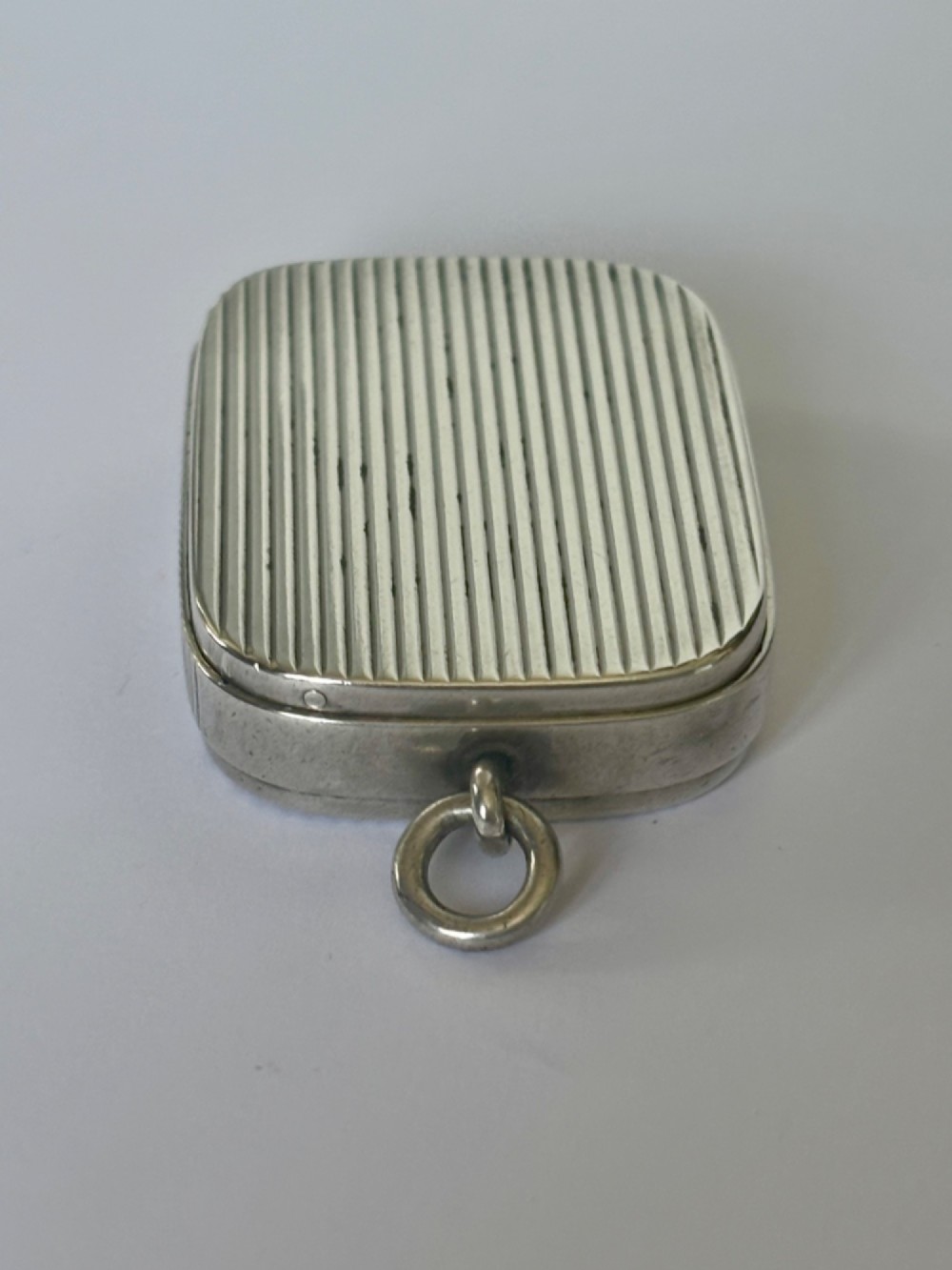 A small rectangular Victorian silver vesta case featuring horizontal reeded engine-turned decoration and an attached side suspension ring. View XI