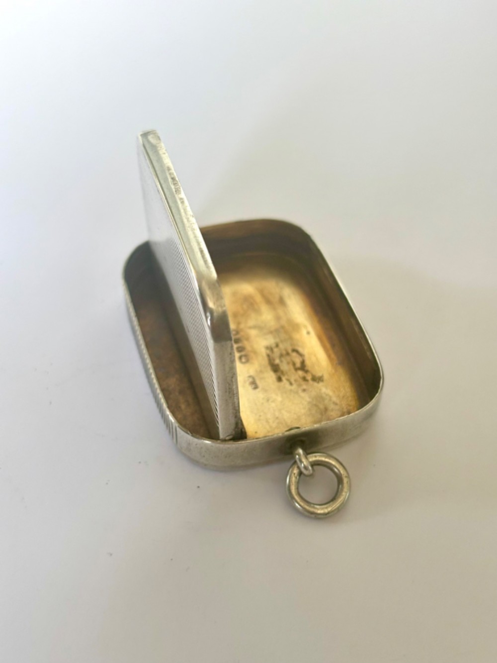 A small rectangular Victorian silver vesta case featuring horizontal reeded engine-turned decoration and an attached side suspension ring. View XIV