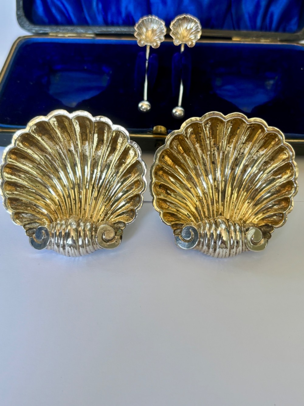An open fitted presentation case containing two shell-shaped silver salt cellars with gilded interiors and two matching shell-bowl spoons. View IX