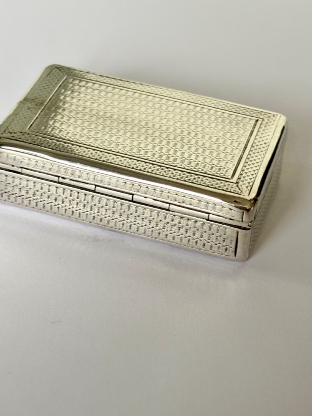 A small rectangular sterling silver snuff box with engine-turned basketweave engraving and a hinged lid. View IV