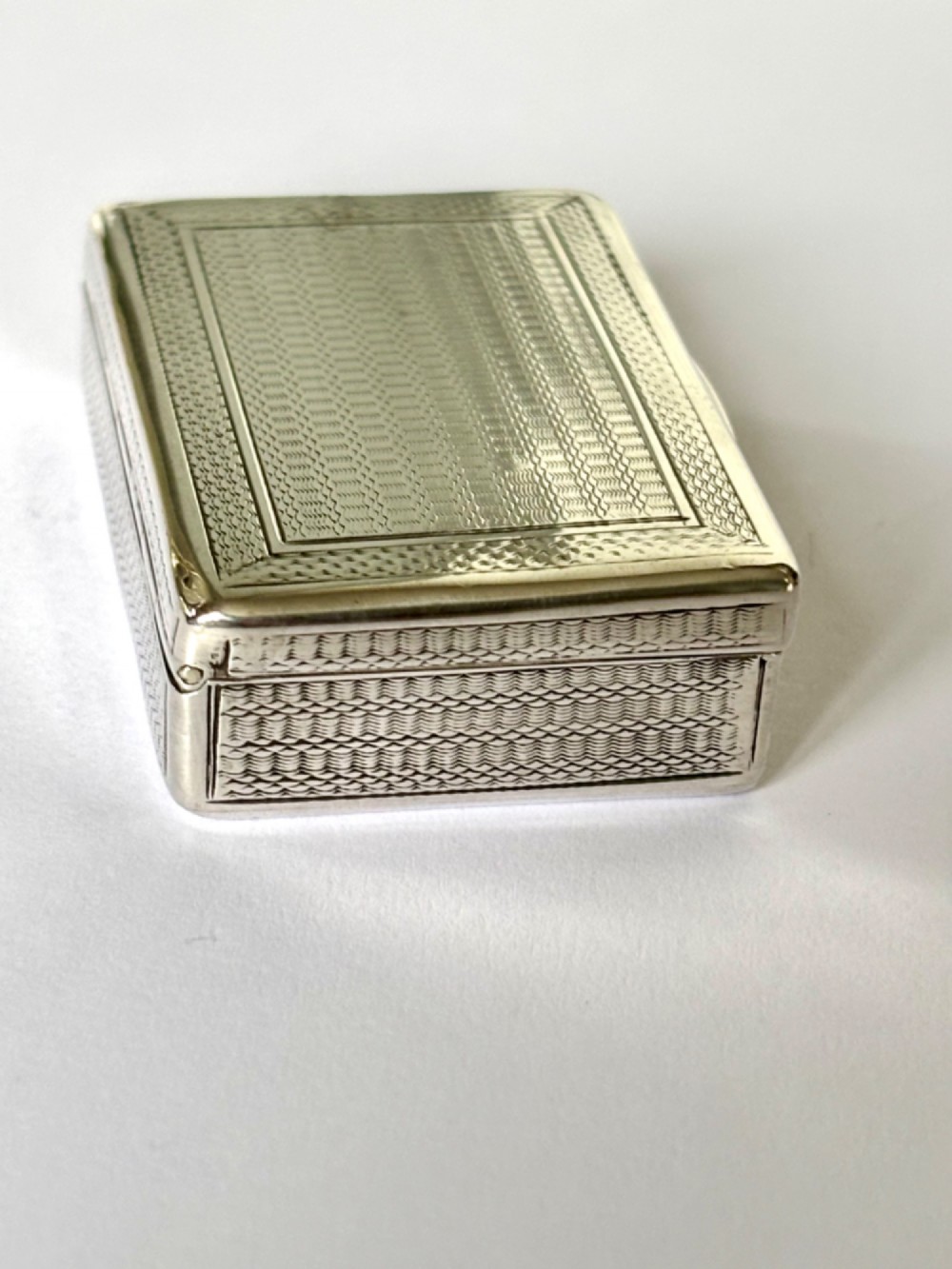 A small rectangular sterling silver snuff box with engine-turned basketweave engraving and a hinged lid. View V