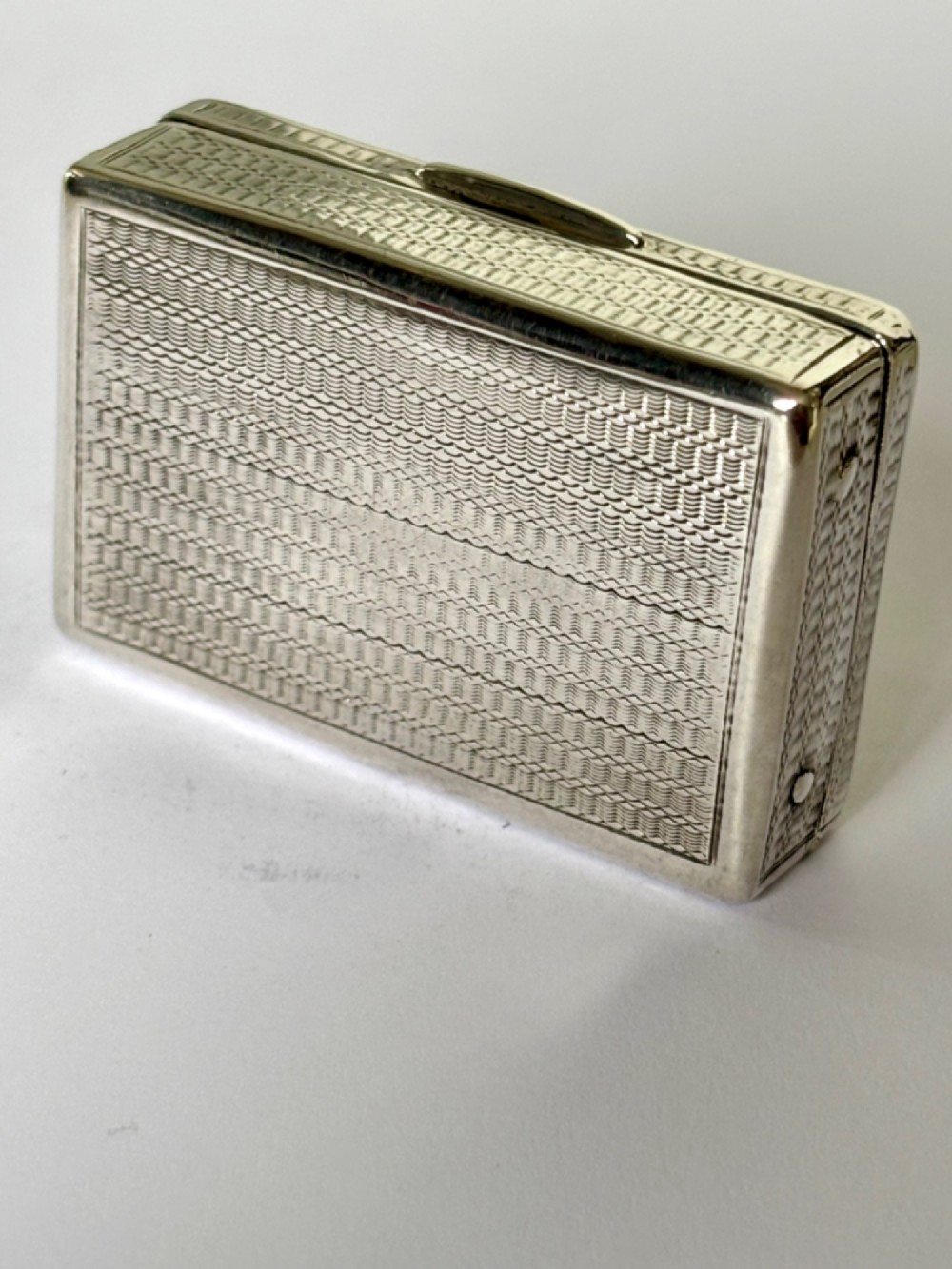 A small rectangular sterling silver snuff box with engine-turned basketweave engraving and a hinged lid. View VI