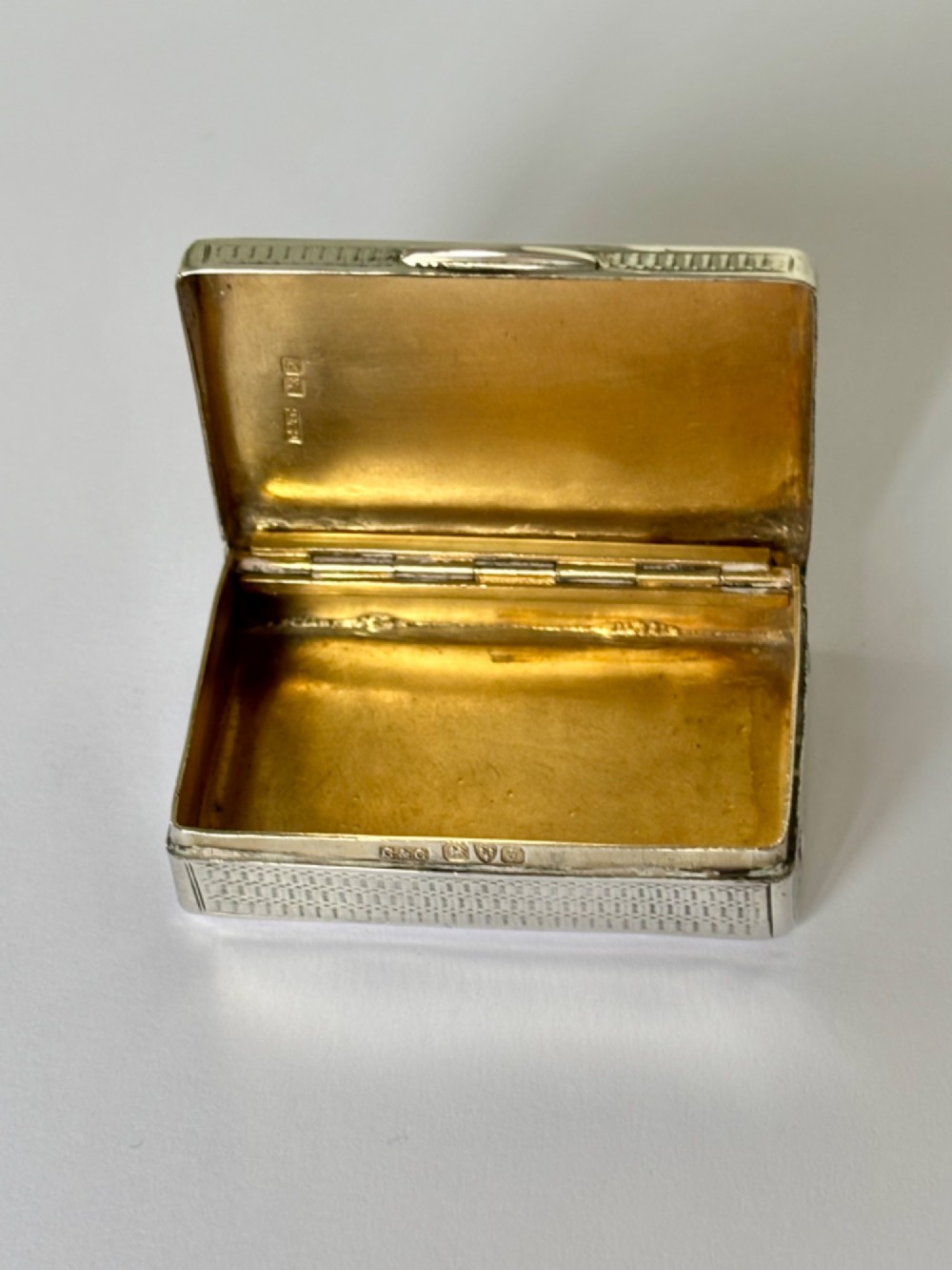 A small rectangular sterling silver snuff box with engine-turned basketweave engraving and a hinged lid. View IX