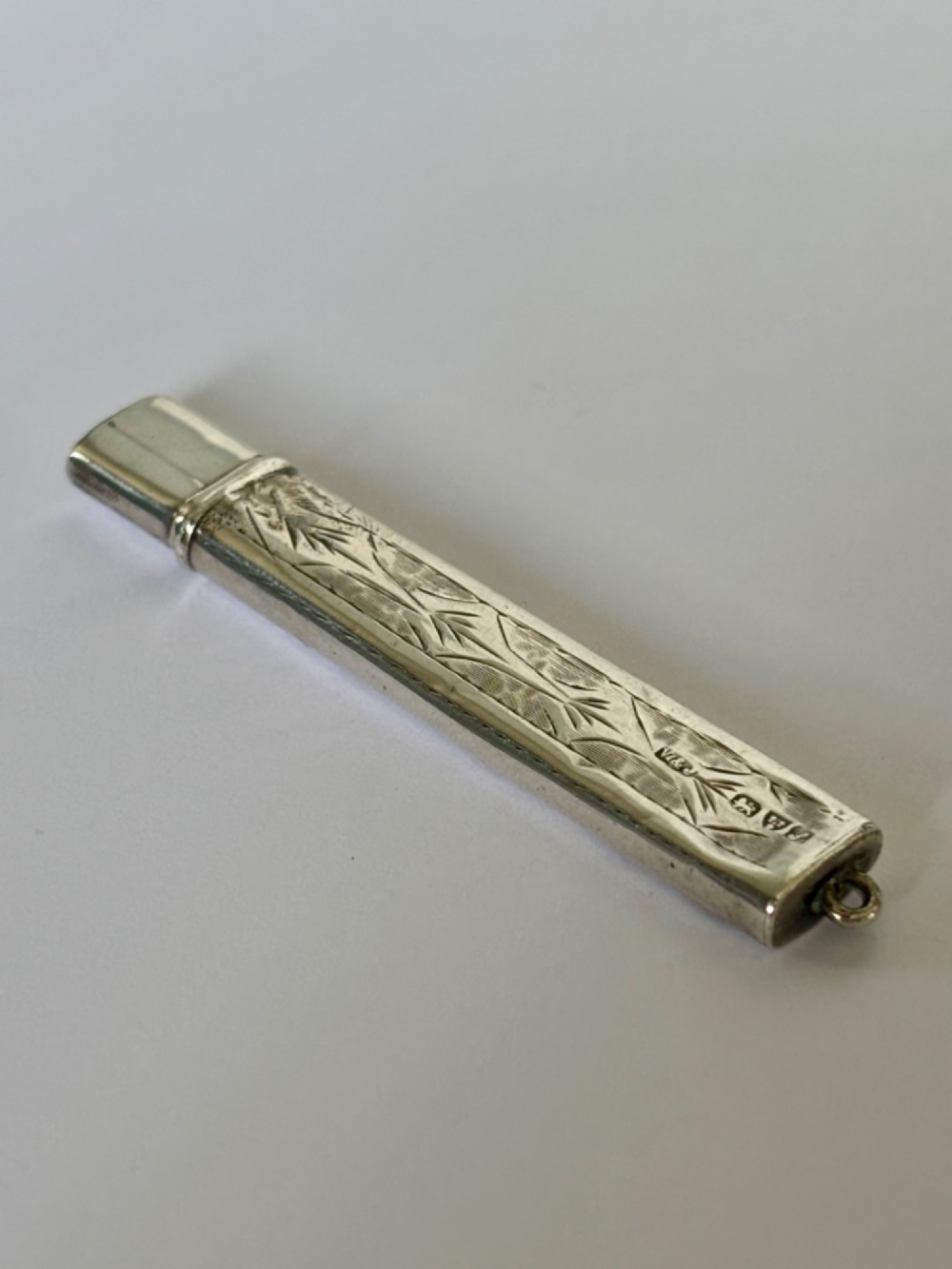An engraved rectangular sterling silver pencil case featuring botanical foliage engraving and Chester hallmark stampings from 1918.