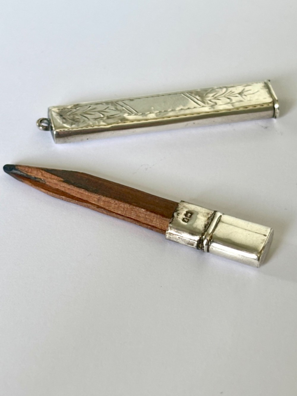 An engraved rectangular sterling silver pencil case featuring botanical foliage engraving and Chester hallmark stampings from 1918. View X