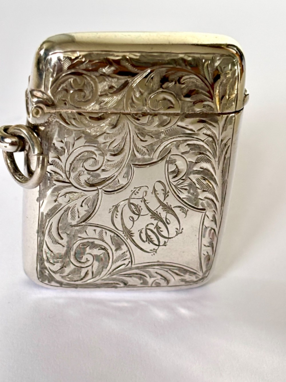 An Edwardian silver vesta case decorated with intricate foliate scroll engraving and a central monogrammed cartouche. View II