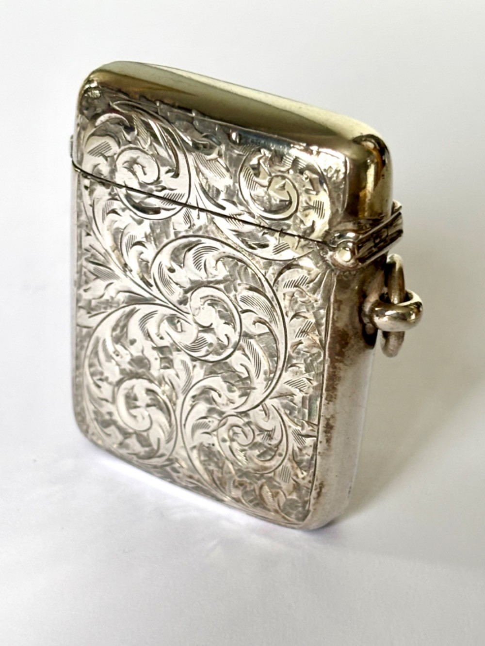 An Edwardian silver vesta case decorated with intricate foliate scroll engraving and a central monogrammed cartouche. View III