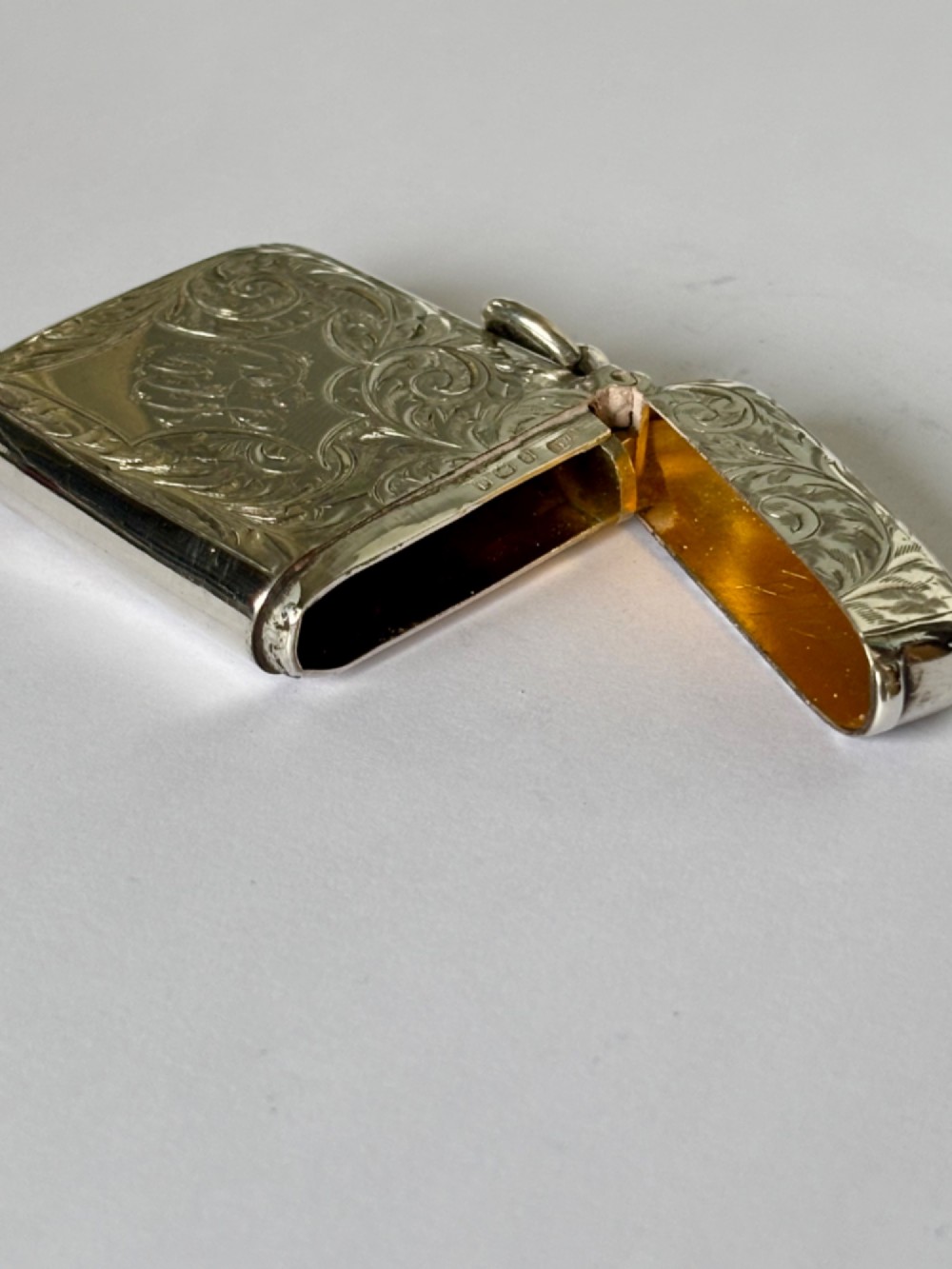 An Edwardian silver vesta case decorated with intricate foliate scroll engraving and a central monogrammed cartouche. View VI