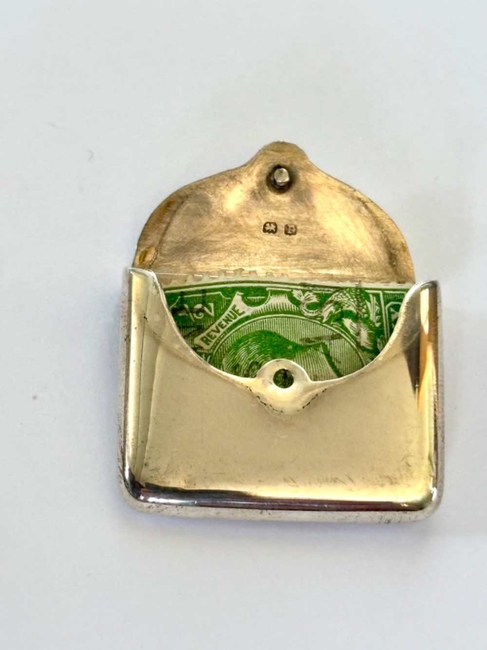 An antique sterling silver envelope-shaped stamp case featuring an engraved border and a suspension ring. View IV