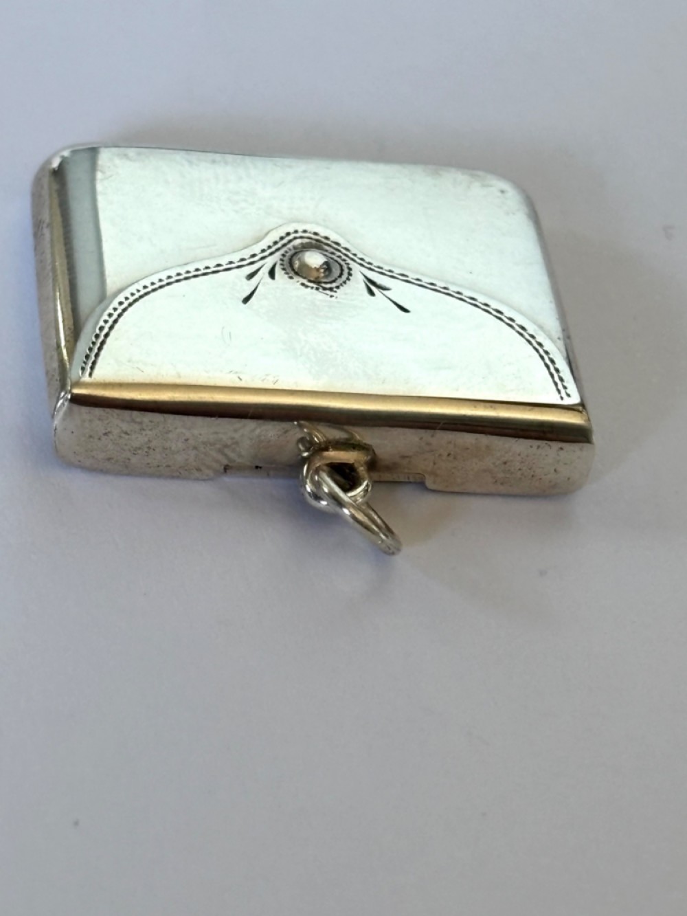 An antique sterling silver envelope-shaped stamp case featuring an engraved border and a suspension ring. View VIII