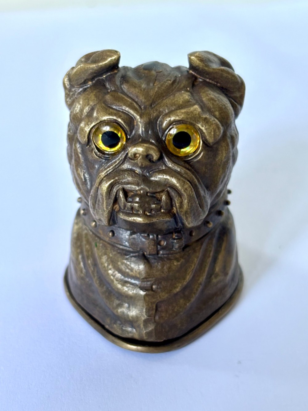 A cast brass table-top vesta case sculpted in the form of a bulldog head featuring inset yellow glass eyes and a studded collar.