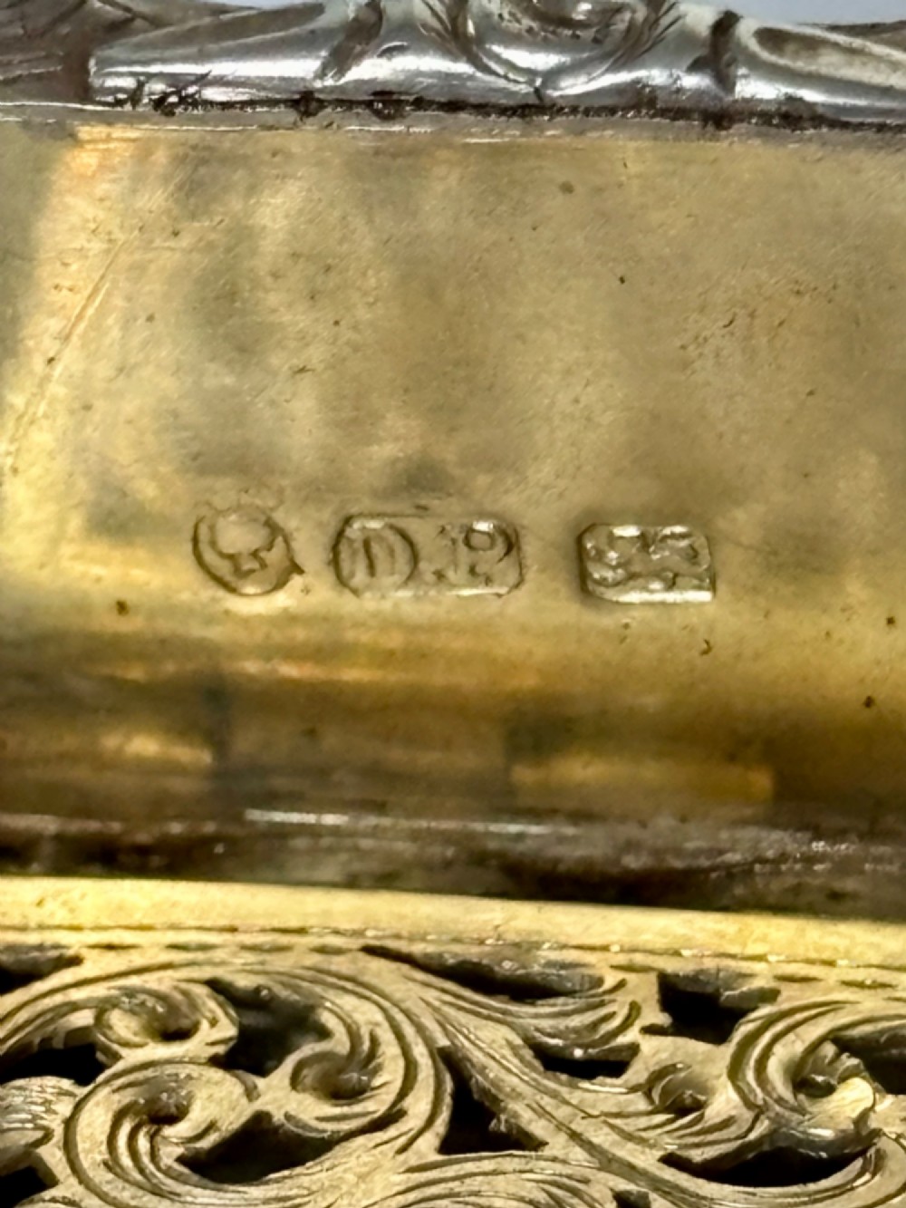 An open early Victorian rectangular silver-gilt vinaigrette showing hallmarks inside the lid and a detailed pierced foliate interior grille. View II