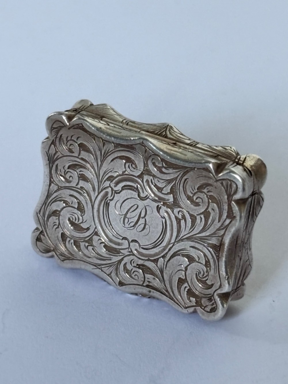An open early Victorian rectangular silver-gilt vinaigrette showing hallmarks inside the lid and a detailed pierced foliate interior grille. View IV