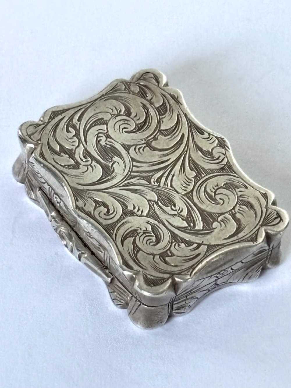 An open early Victorian rectangular silver-gilt vinaigrette showing hallmarks inside the lid and a detailed pierced foliate interior grille. View VIII