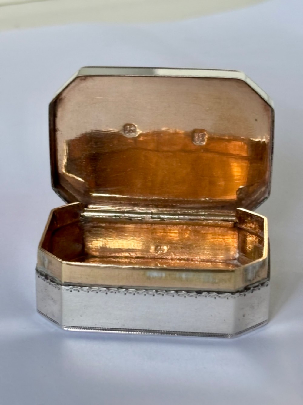 An octagonal Georgian sterling silver snuff box featuring bright-cut foliate engraving and an engraved central oval monogram. View II