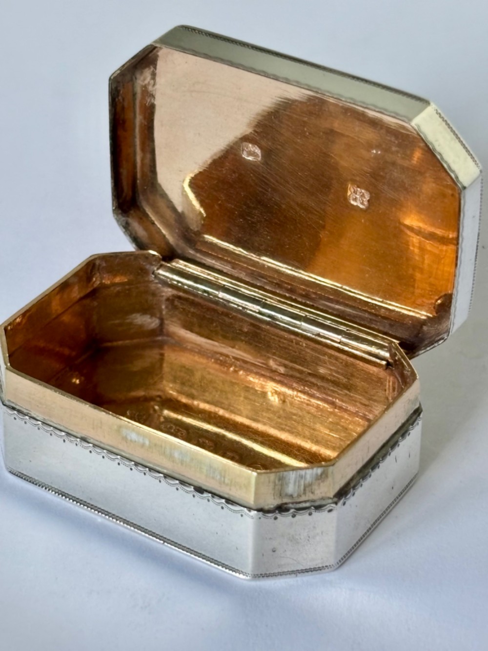 An octagonal Georgian sterling silver snuff box featuring bright-cut foliate engraving and an engraved central oval monogram. View III