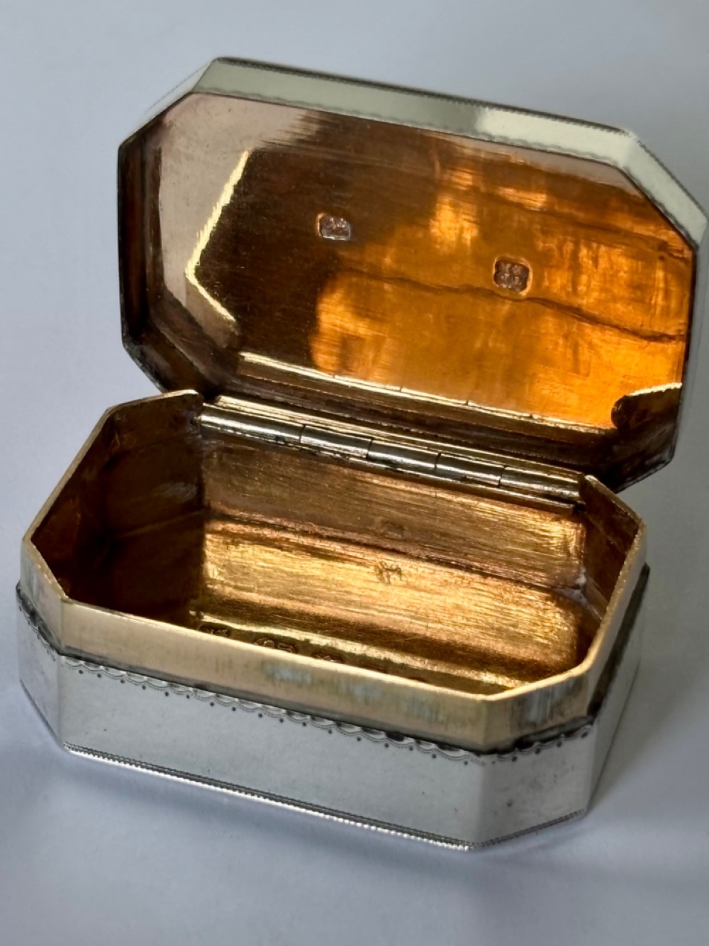 An octagonal Georgian sterling silver snuff box featuring bright-cut foliate engraving and an engraved central oval monogram. View IV