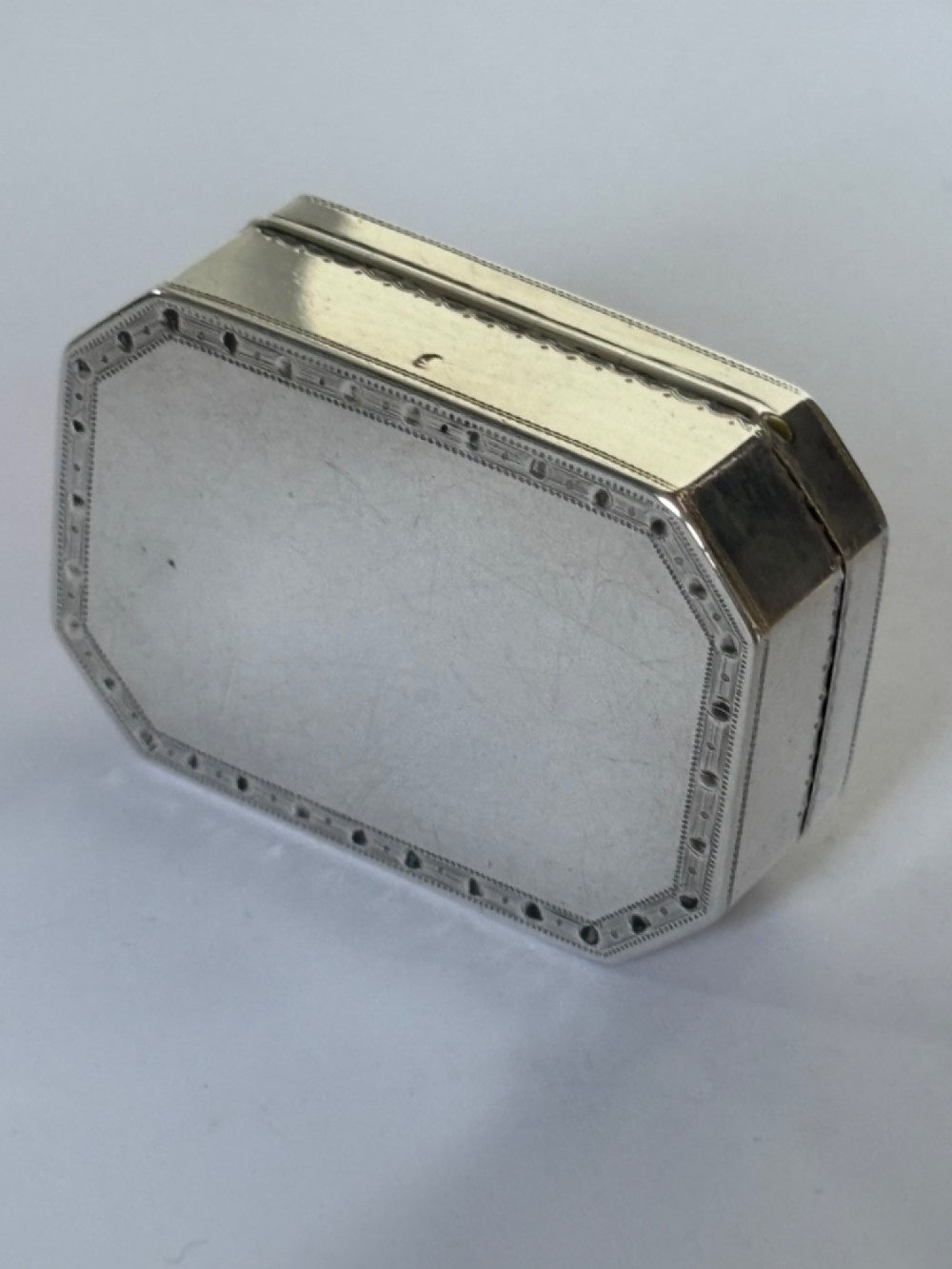 An octagonal Georgian sterling silver snuff box featuring bright-cut foliate engraving and an engraved central oval monogram. View VI