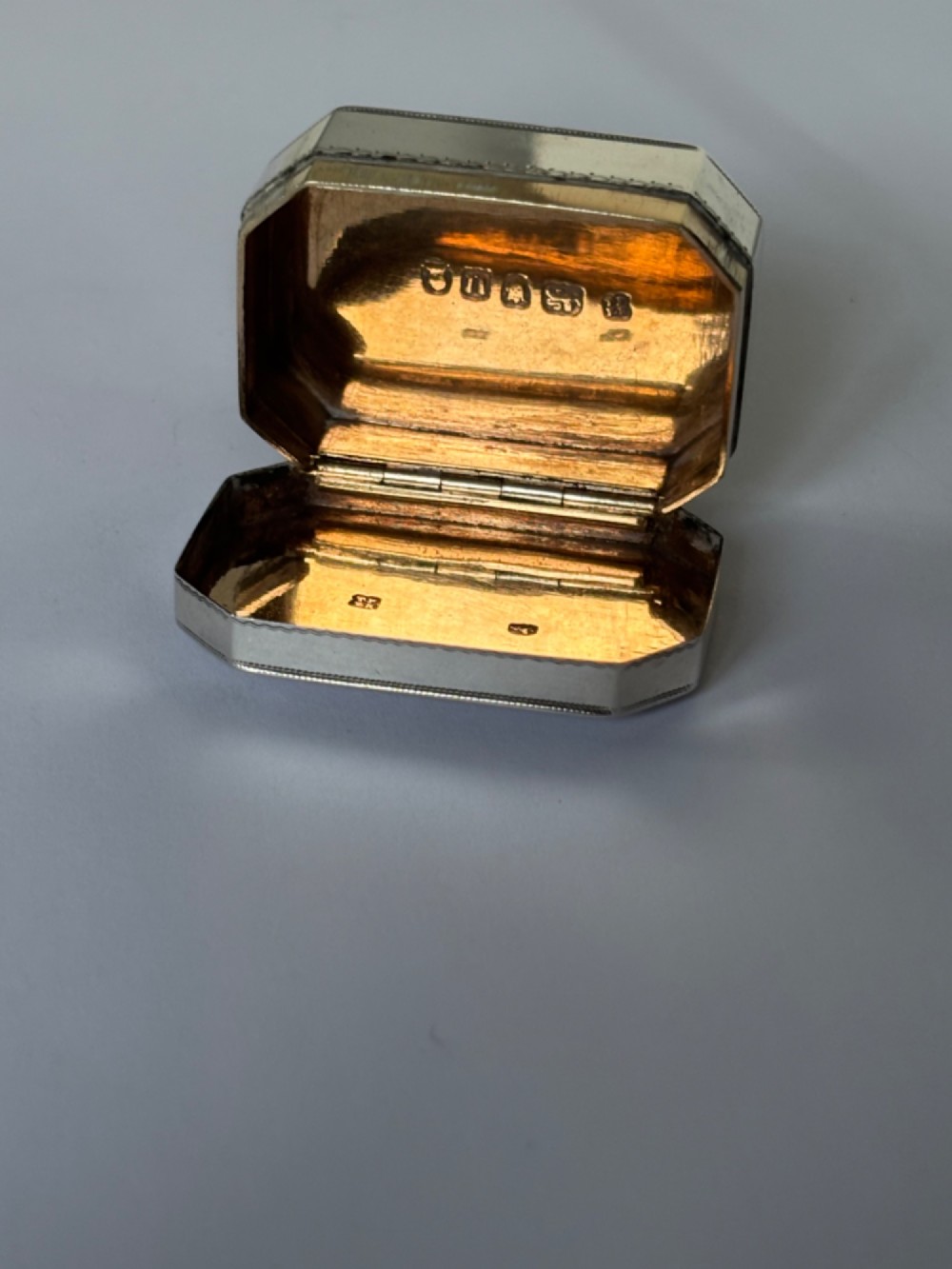 An octagonal Georgian sterling silver snuff box featuring bright-cut foliate engraving and an engraved central oval monogram. View XII