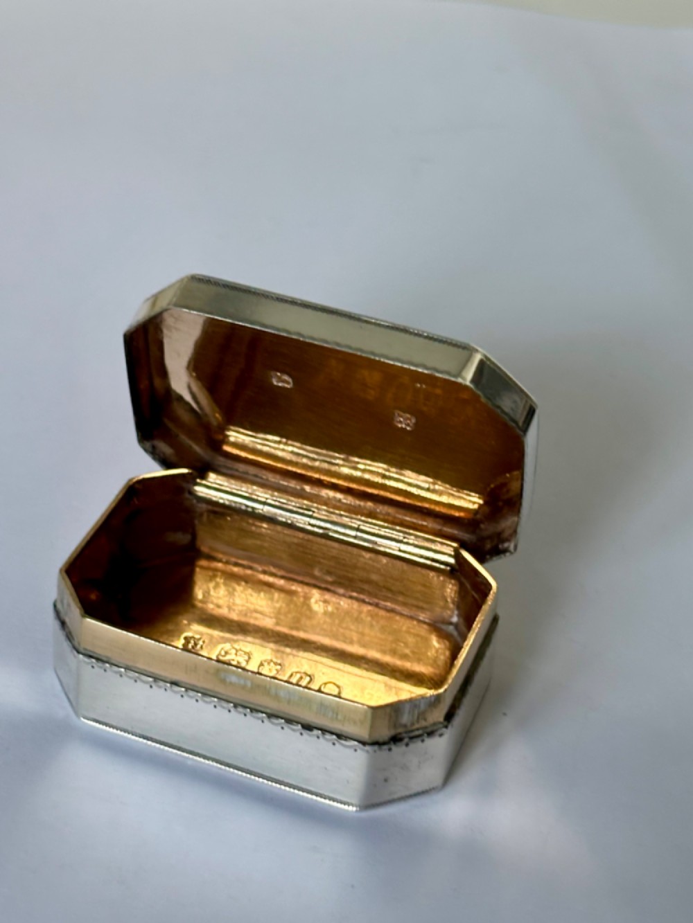 An octagonal Georgian sterling silver snuff box featuring bright-cut foliate engraving and an engraved central oval monogram. View XIII