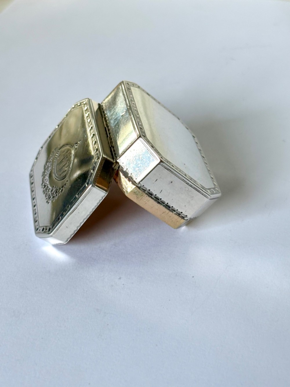 An octagonal Georgian sterling silver snuff box featuring bright-cut foliate engraving and an engraved central oval monogram. View XIV