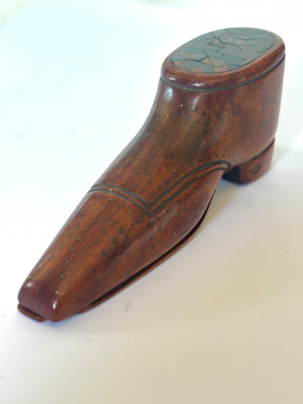 A 19th-century carved wooden shoe-form snuff box featuring brass pique pinwork and a geometric parquetry inlaid lid. View V
