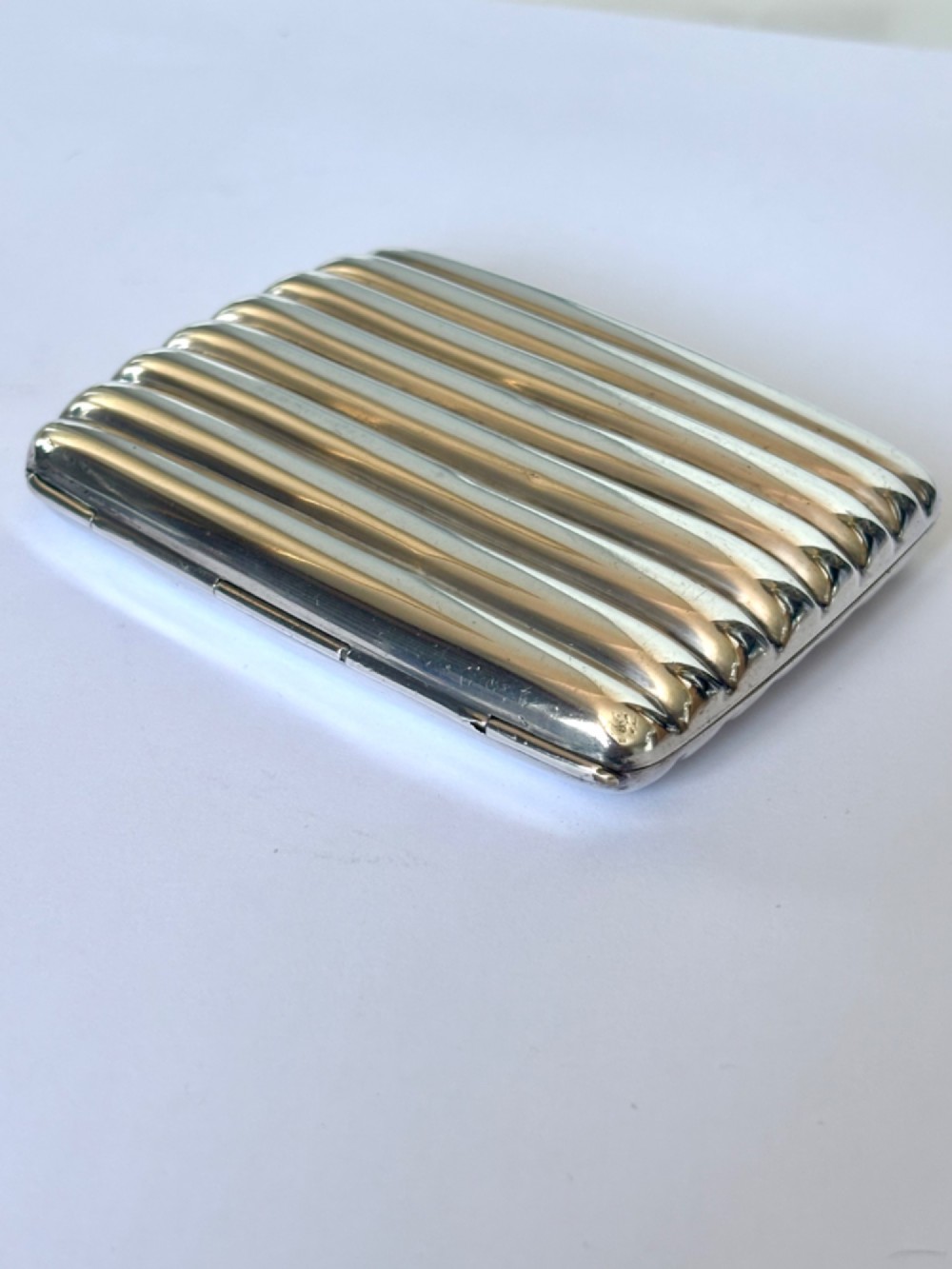 A curved sterling silver cigarette case featuring vertical fluted reeding and a push-button release mechanism. View II