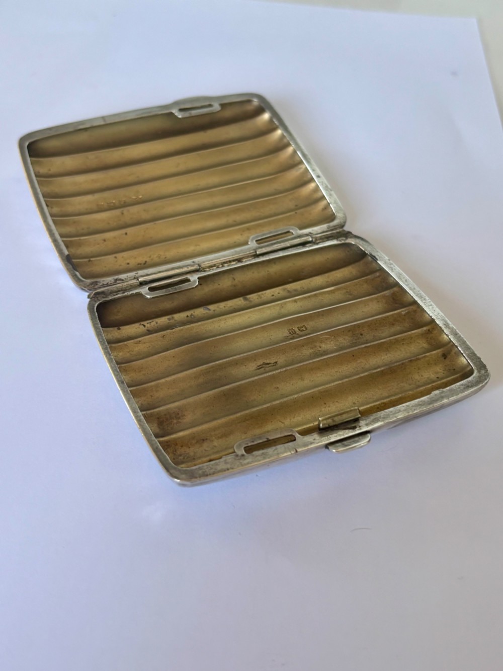 A curved sterling silver cigarette case featuring vertical fluted reeding and a push-button release mechanism. View VIII
