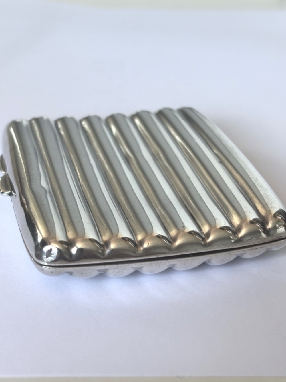 A curved sterling silver cigarette case featuring vertical fluted reeding and a push-button release mechanism. View X
