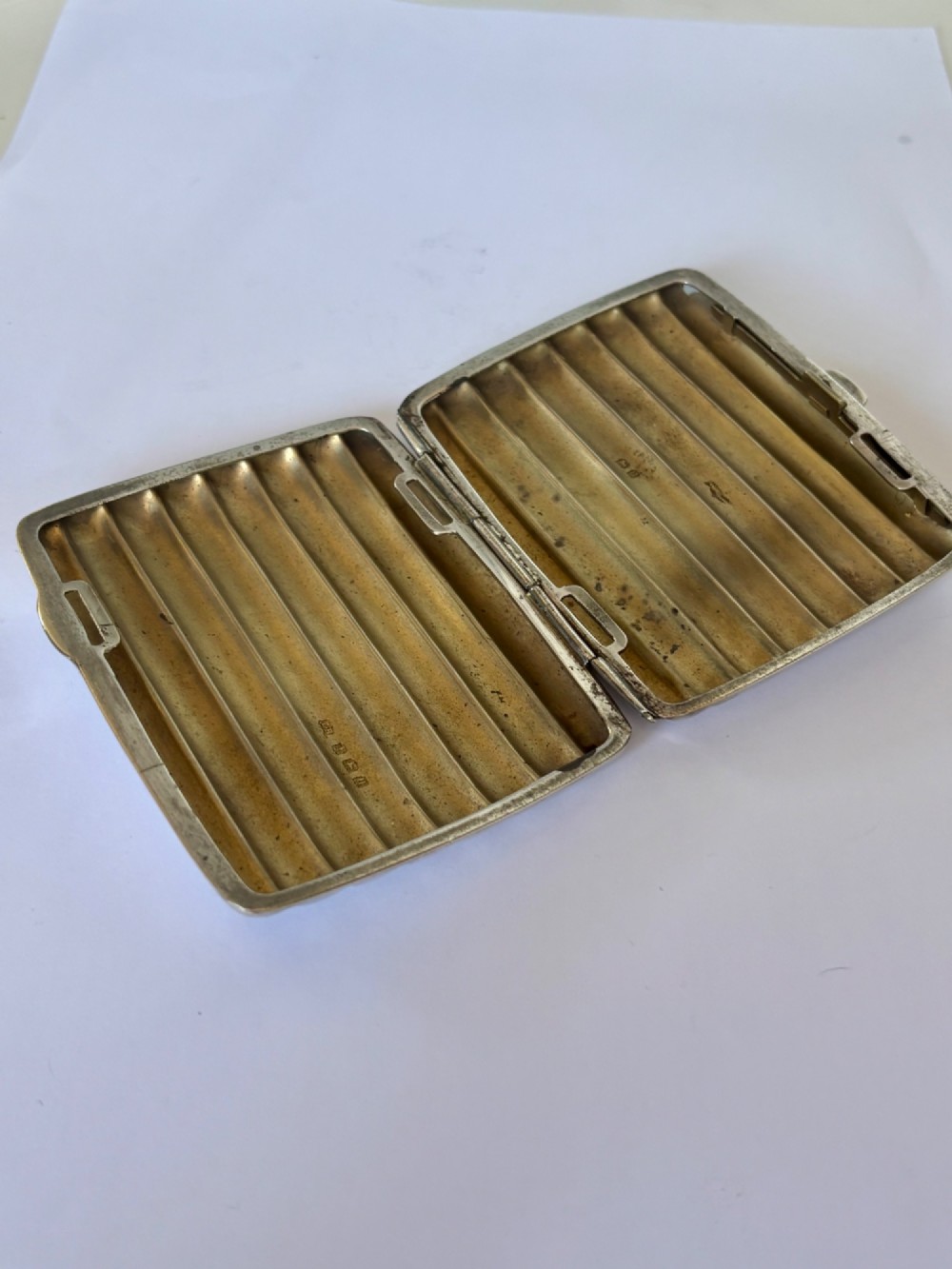 A curved sterling silver cigarette case featuring vertical fluted reeding and a push-button release mechanism. View XI
