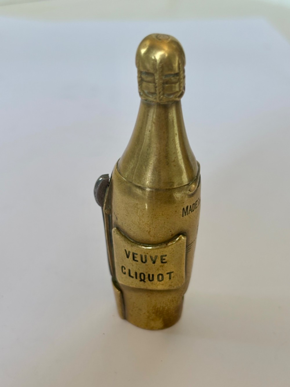 A nineteenth-century brass novelty vesta case and cigar cutter shaped like a champagne bottle with stamped Veuve Clicquot lettering.