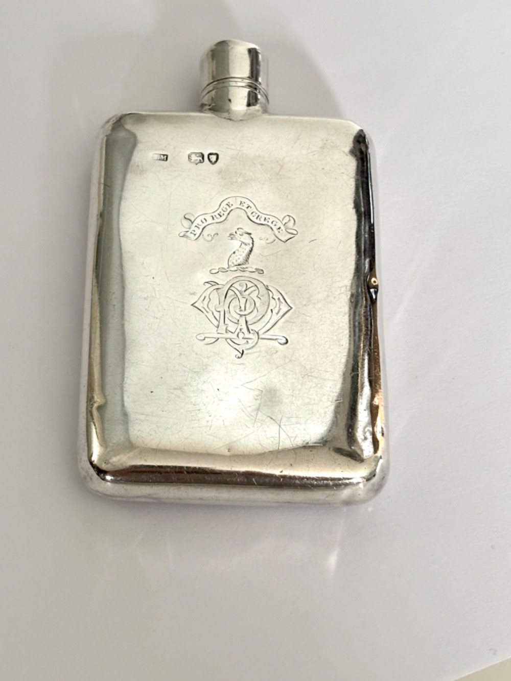 A Victorian sterling silver hip flask featuring an engraved crest, family monogram, and official British silver hallmarks.