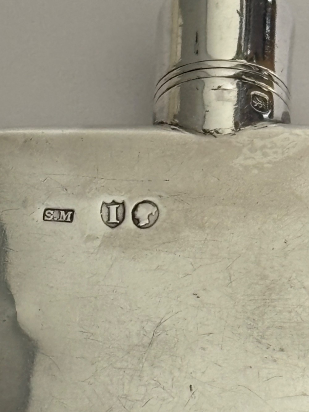 A Victorian sterling silver hip flask featuring an engraved crest, family monogram, and official British silver hallmarks. View II
