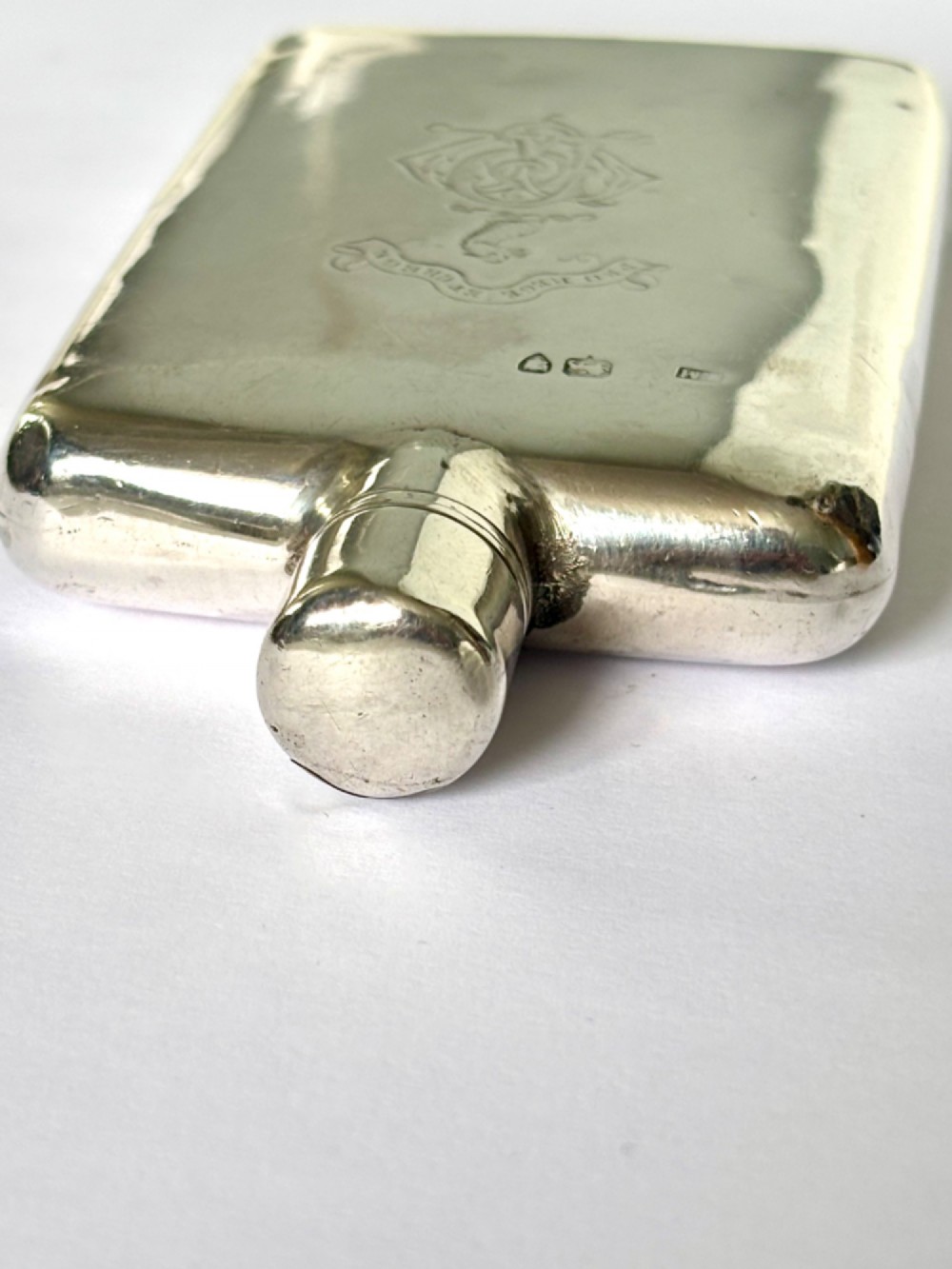 A Victorian sterling silver hip flask featuring an engraved crest, family monogram, and official British silver hallmarks. View V