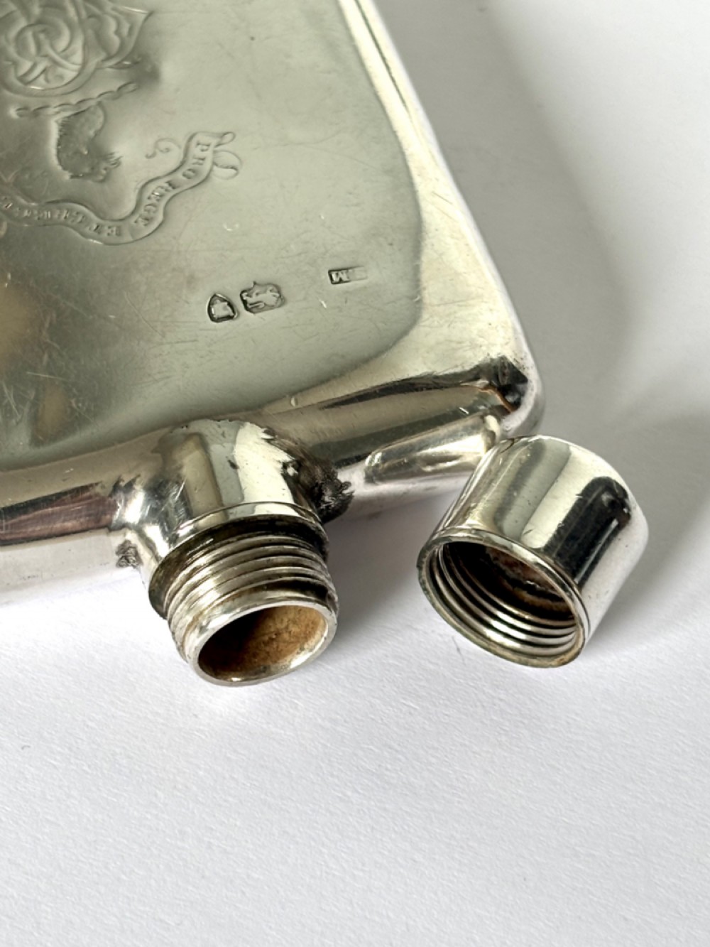 A Victorian sterling silver hip flask featuring an engraved crest, family monogram, and official British silver hallmarks. View IX