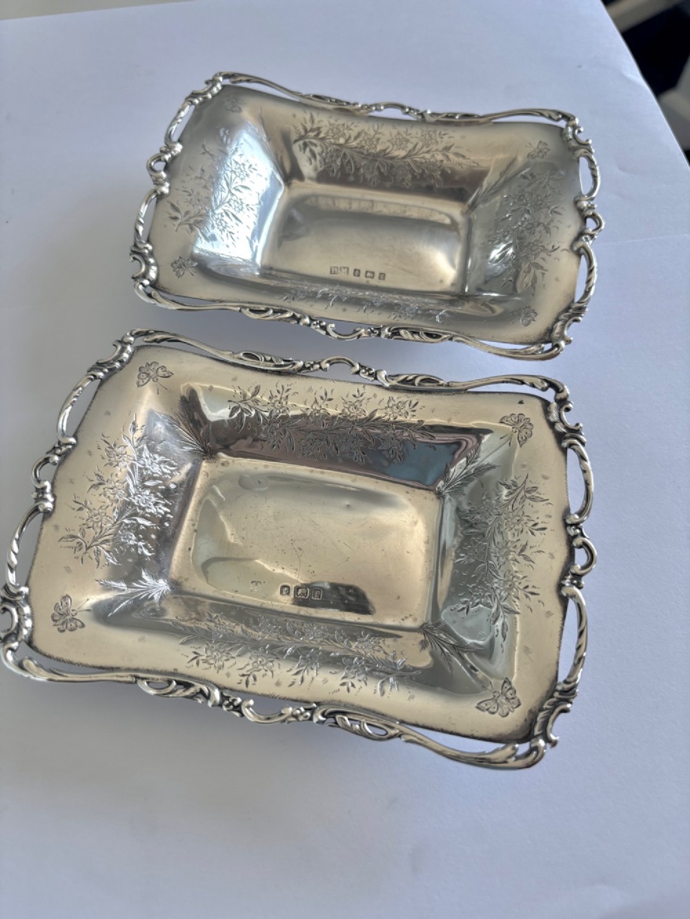 A pair of rectangular Edwardian sterling silver trinket dishes featuring pierced scrollwork borders and engraved floral decoration. View III