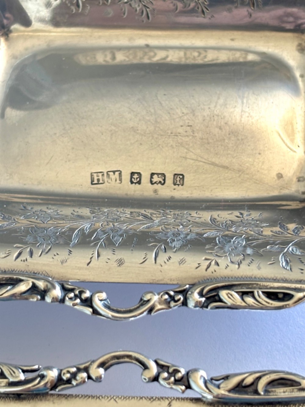 A pair of rectangular Edwardian sterling silver trinket dishes featuring pierced scrollwork borders and engraved floral decoration. View IV