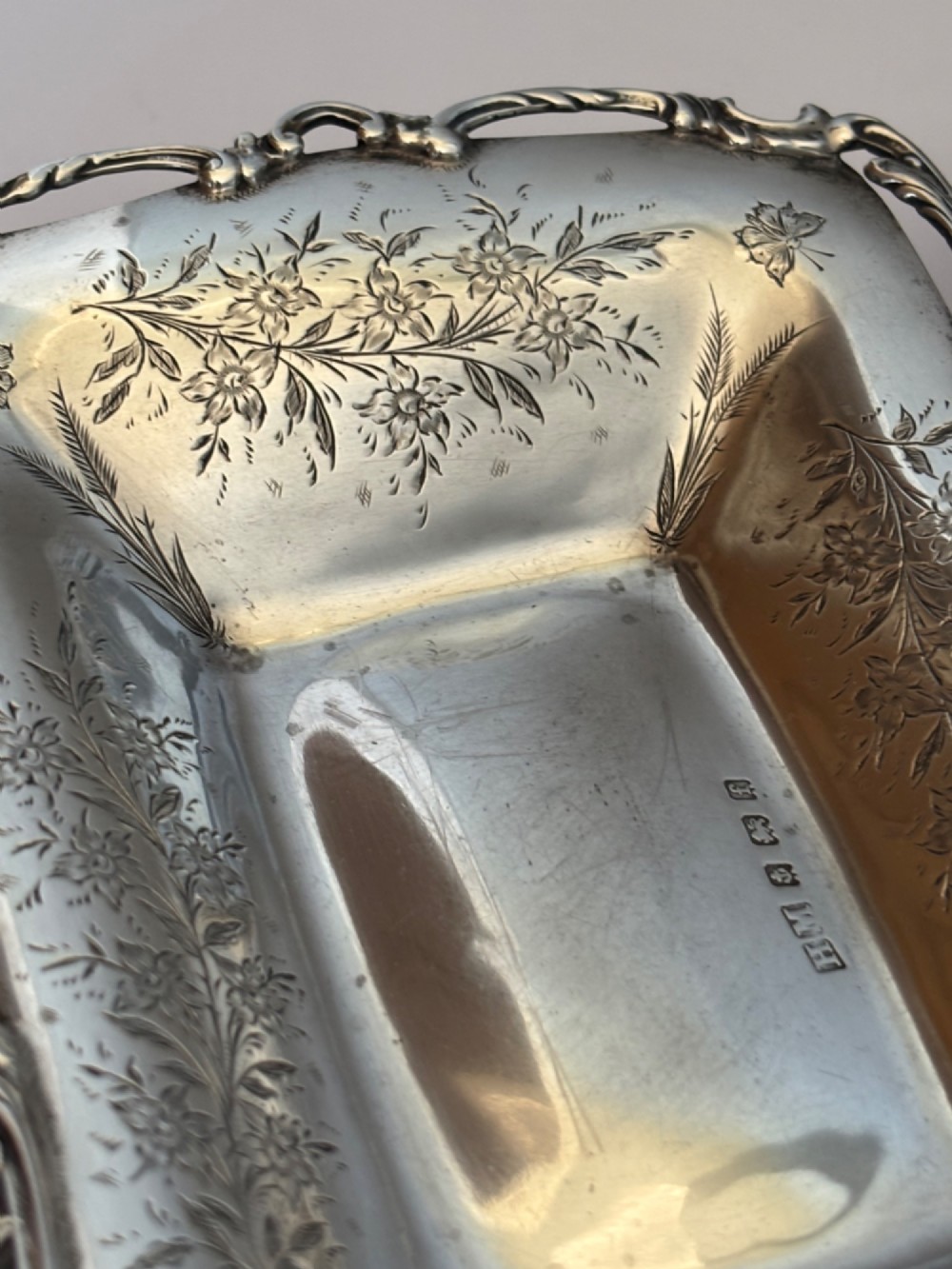 A pair of rectangular Edwardian sterling silver trinket dishes featuring pierced scrollwork borders and engraved floral decoration. View VII