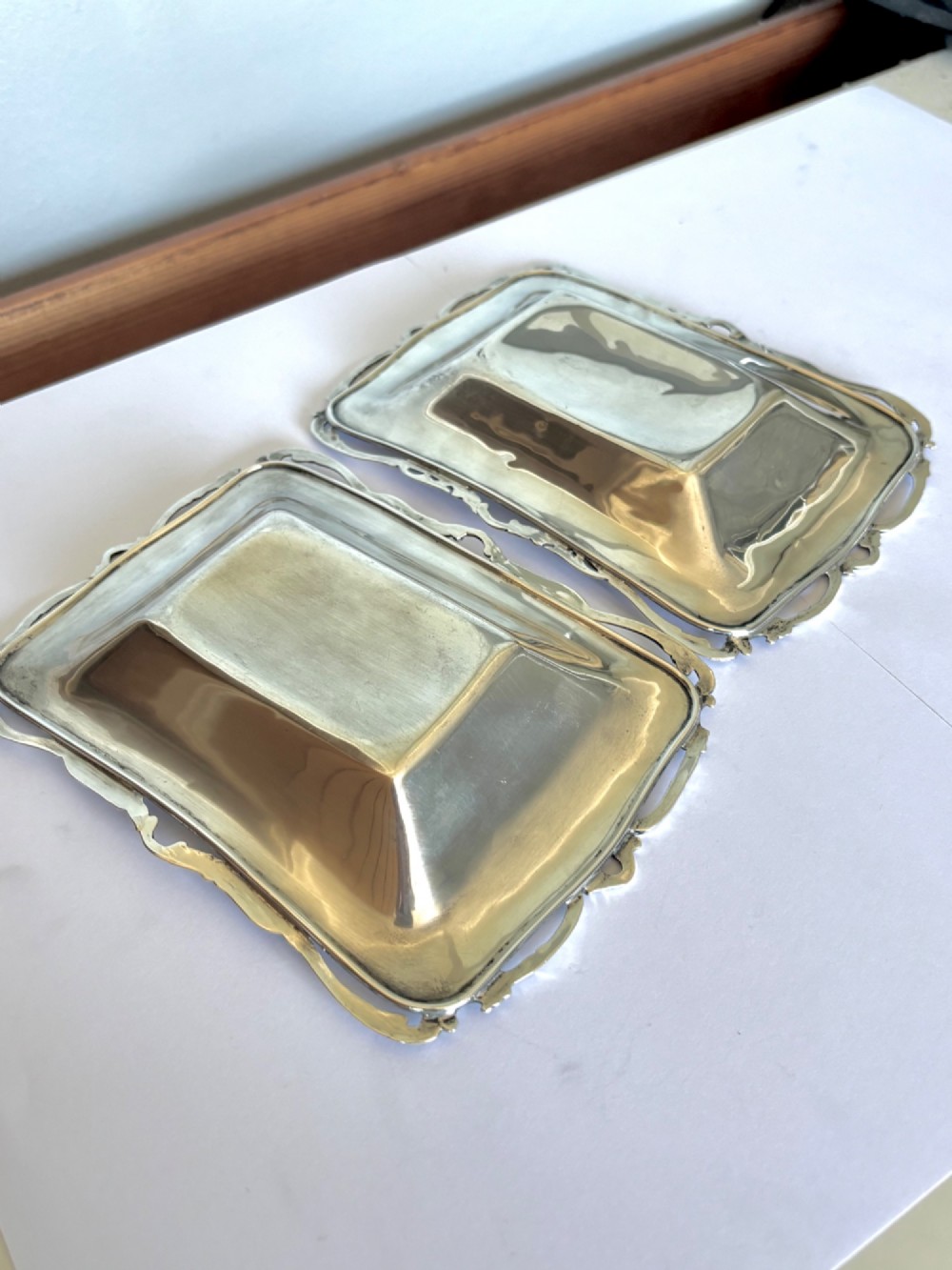 A pair of rectangular Edwardian sterling silver trinket dishes featuring pierced scrollwork borders and engraved floral decoration. View VIII